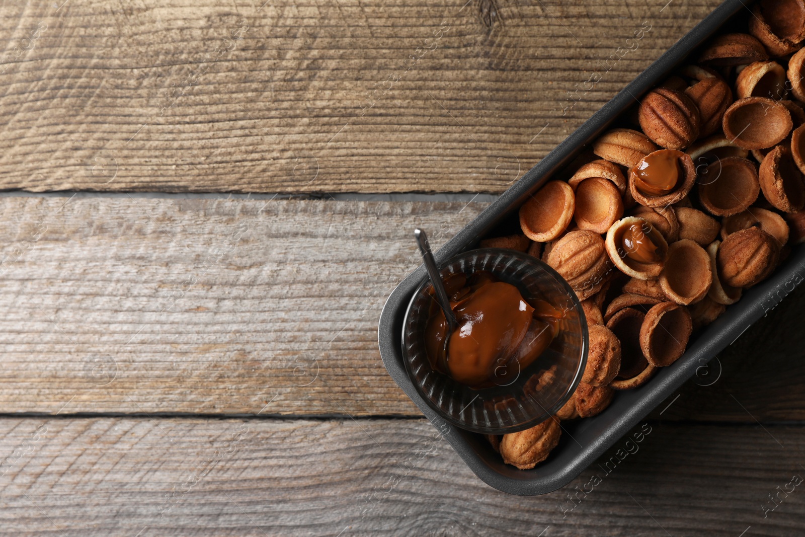 Photo of Making walnut shaped cookies. Cooked dough and caramelized condensed milk on wooden table, top view. Space for text