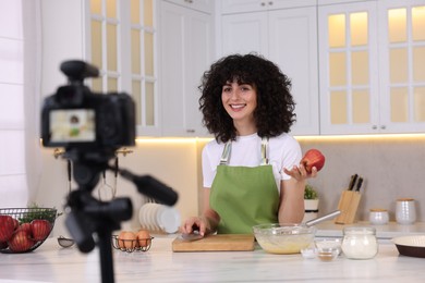 Photo of Smiling food blogger explaining something while recording video in kitchen