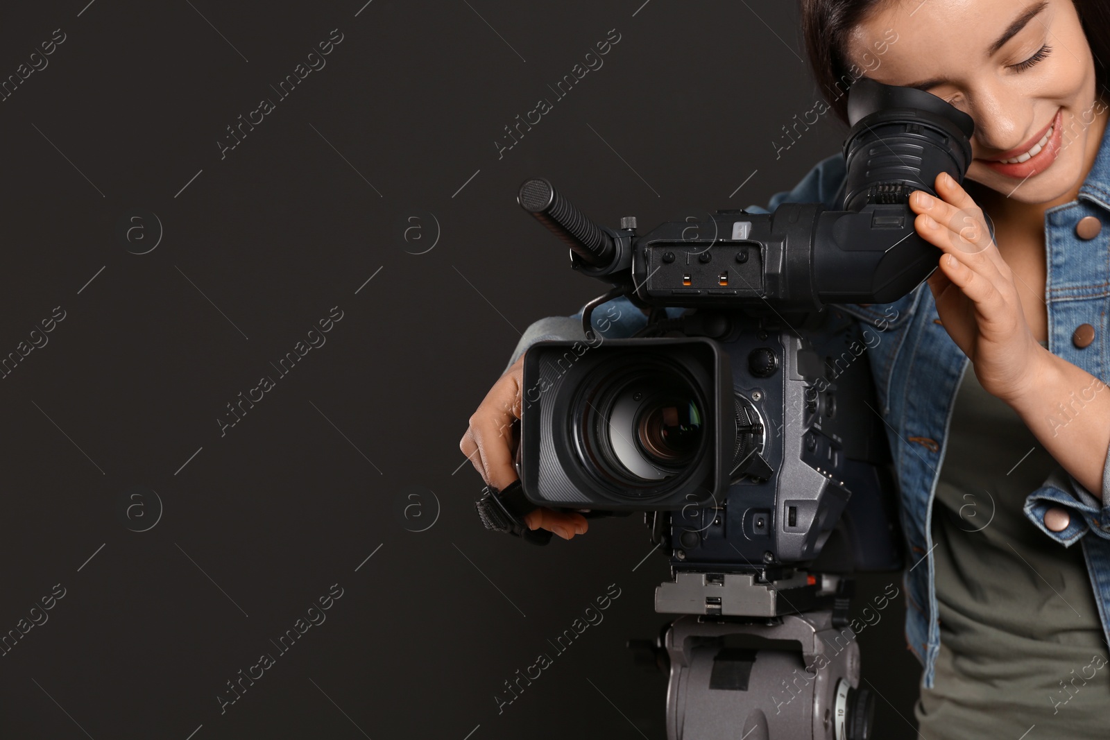 Photo of Operator with professional video camera on black background, space for text