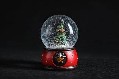 Snow globe with Christmas tree on dark background