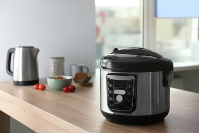 Modern multi cooker and ingredients on table in kitchen, space for text