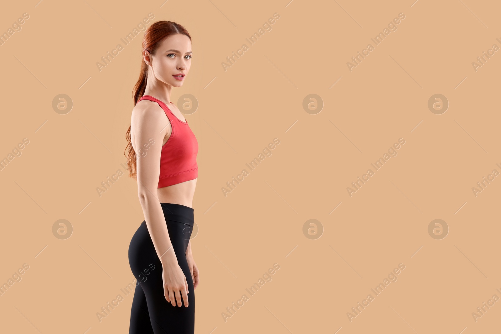 Photo of Young woman in sportswear on beige background, space for text