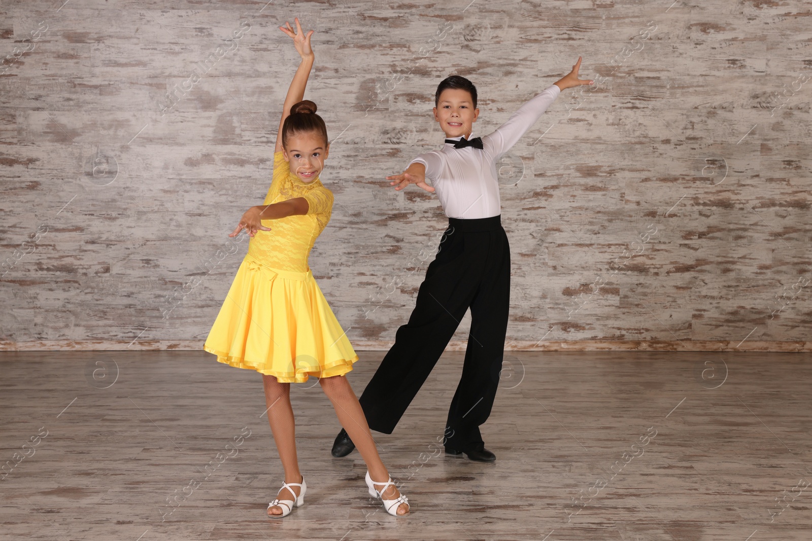 Photo of Beautifully dressed couple of kids dancing together in studio