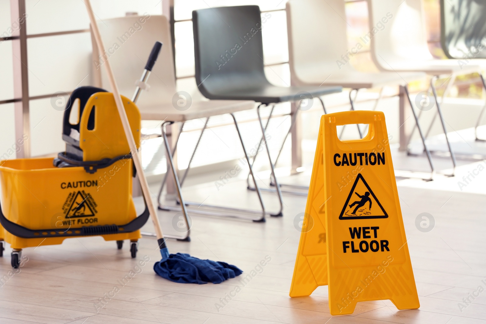 Photo of Safety sign with phrase Caution wet floor and mop bucket, indoors. Cleaning service