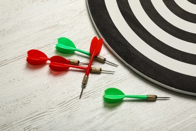 Photo of Dart board with color arrows on white wooden background