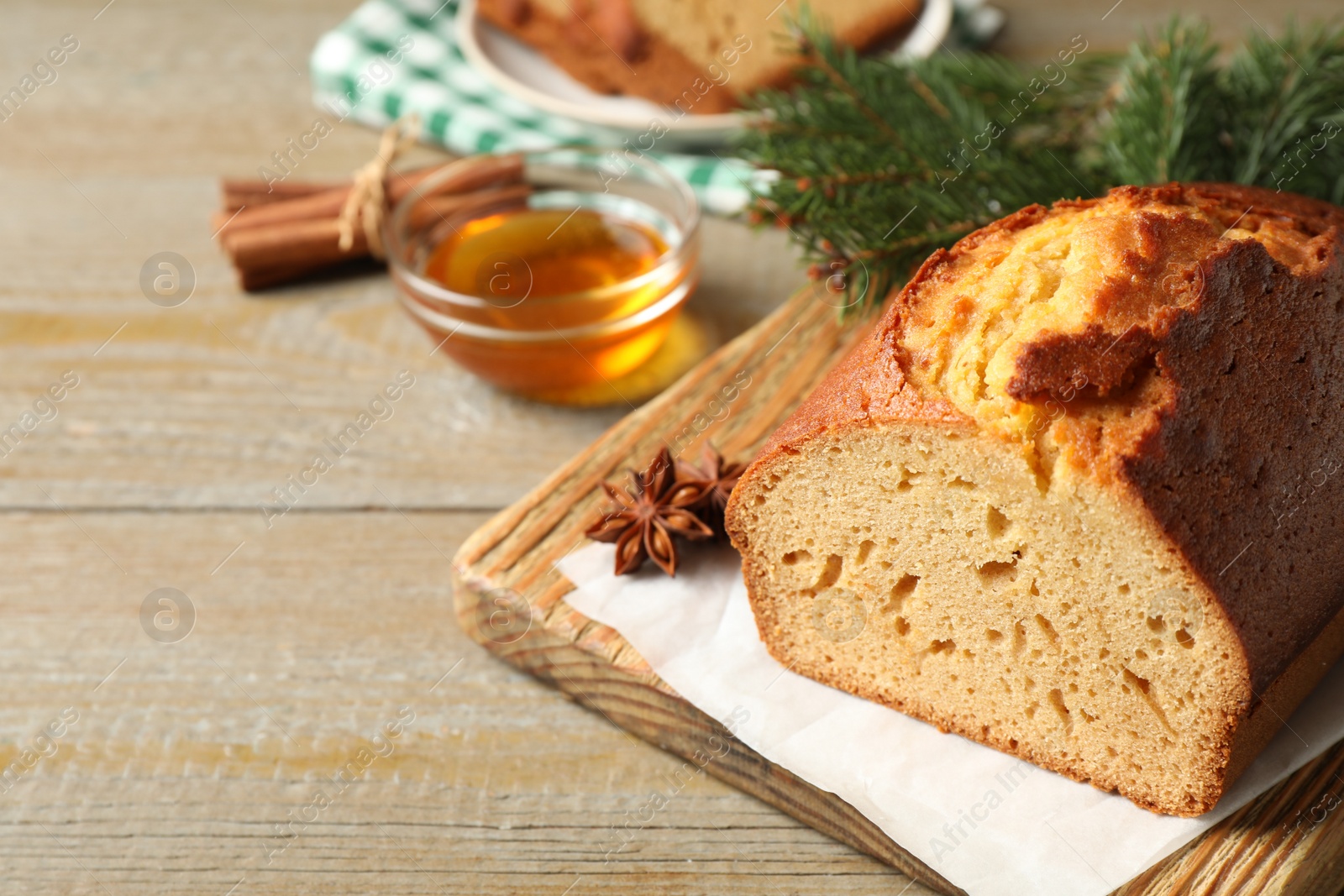 Photo of Delicious gingerbread cake and fir branch on wooden table. Space for text