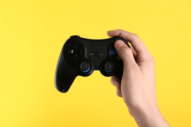 Photo of Man using wireless game controller on yellow background, closeup