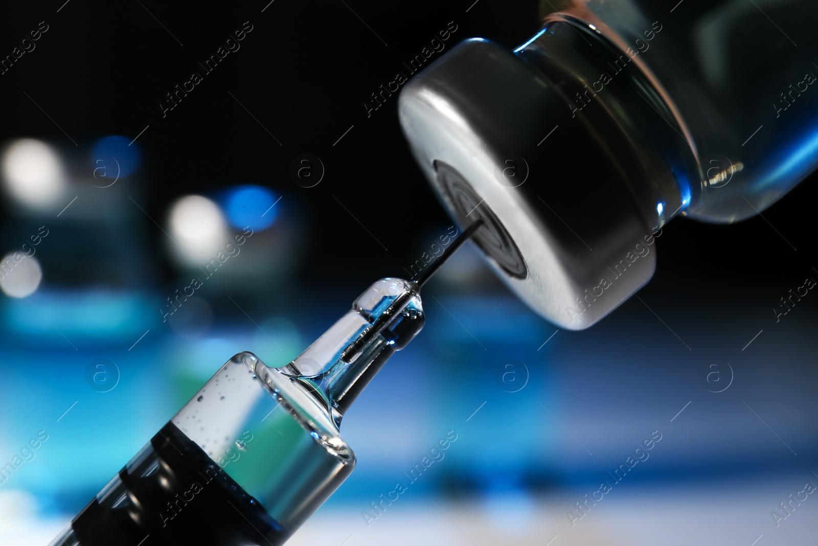 Photo of Filling syringe with vaccine from vial on blurred background, closeup