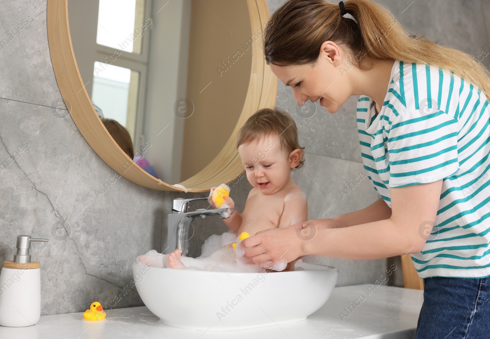 Photo of Mother washing her little baby in sink at home