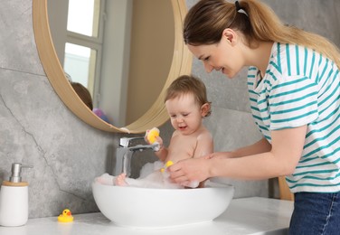 Photo of Mother washing her little baby in sink at home
