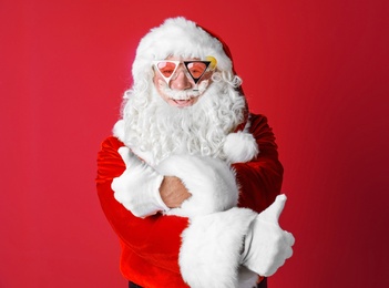 Authentic Santa Claus wearing sunglasses on color background