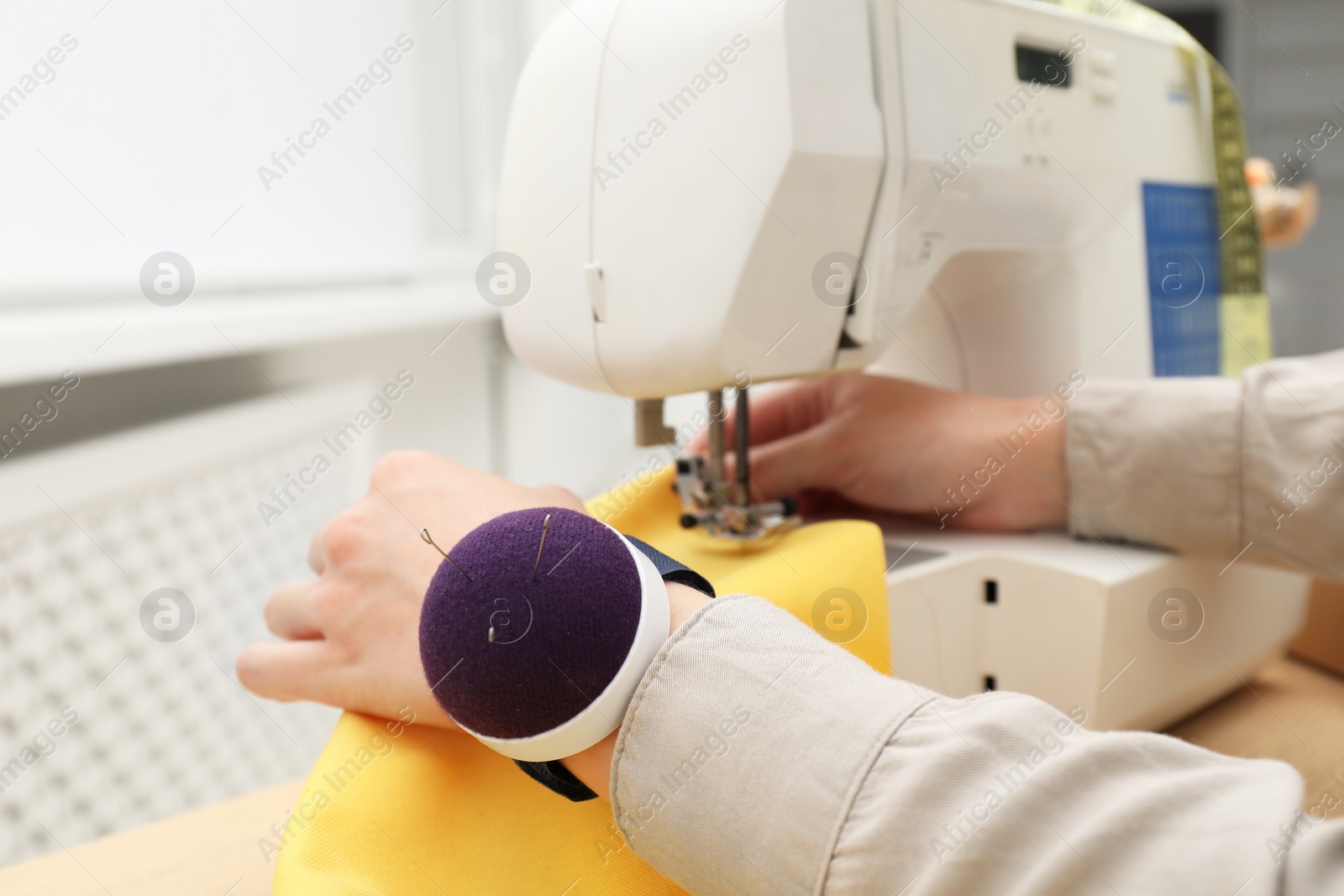 Photo of Seamstress working with sewing machine indoors, closeup