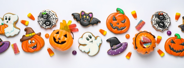 Photo of Tasty cookies and sweets for Halloween party on white table, flat lay