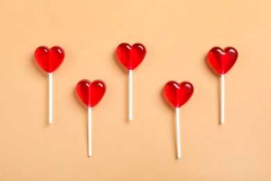 Photo of Sweet heart shaped lollipops on beige background, flat lay. Valentine's day celebration
