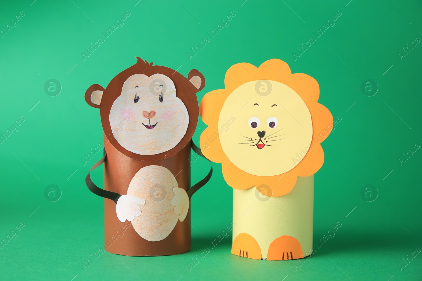 Photo of Toy monkey and lion made from toilet paper hubs on green background. Children's handmade ideas