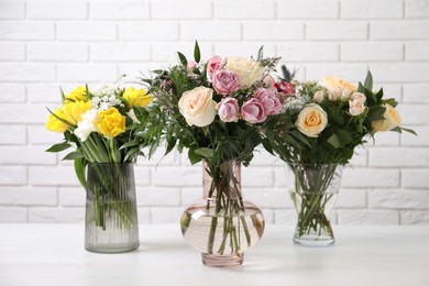 Photo of Beautiful bouquets with fresh flowers on table against white brick wall