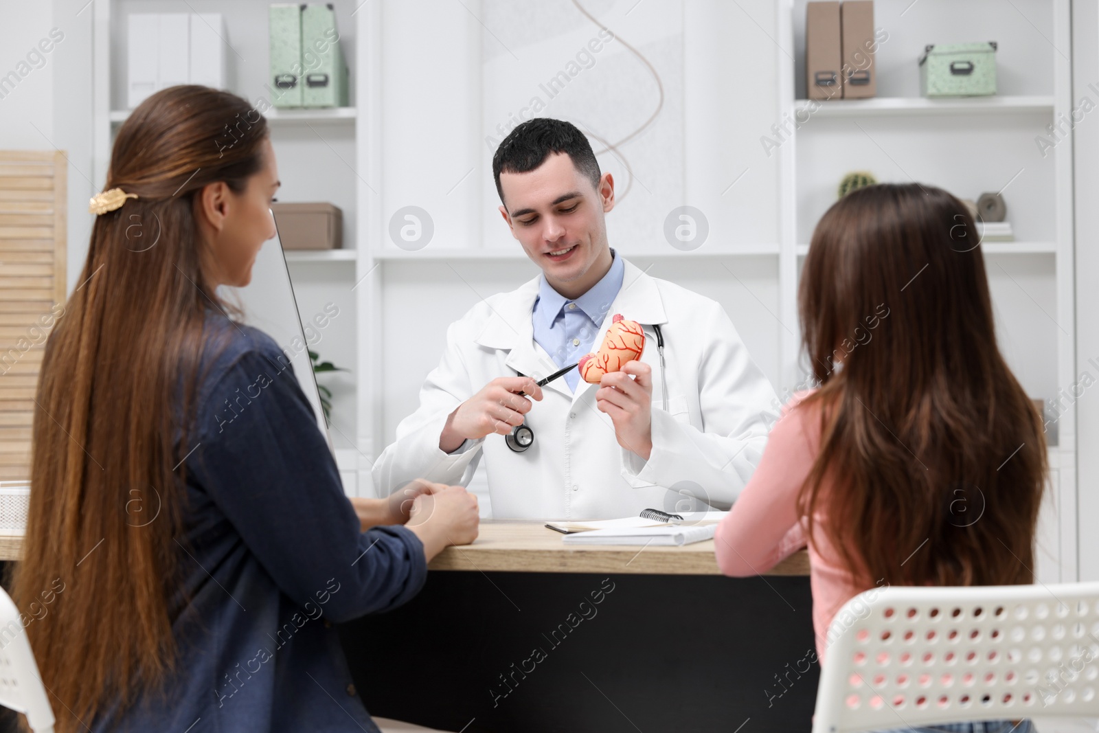 Photo of Gastroenterologist with model of stomach consulting woman and her daughter in clinic