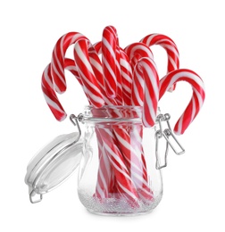 Glass jar with sweet Christmas candy canes on white background