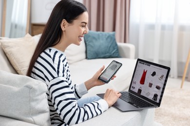 Photo of Beautiful young woman with smartphone and laptop shopping online at home