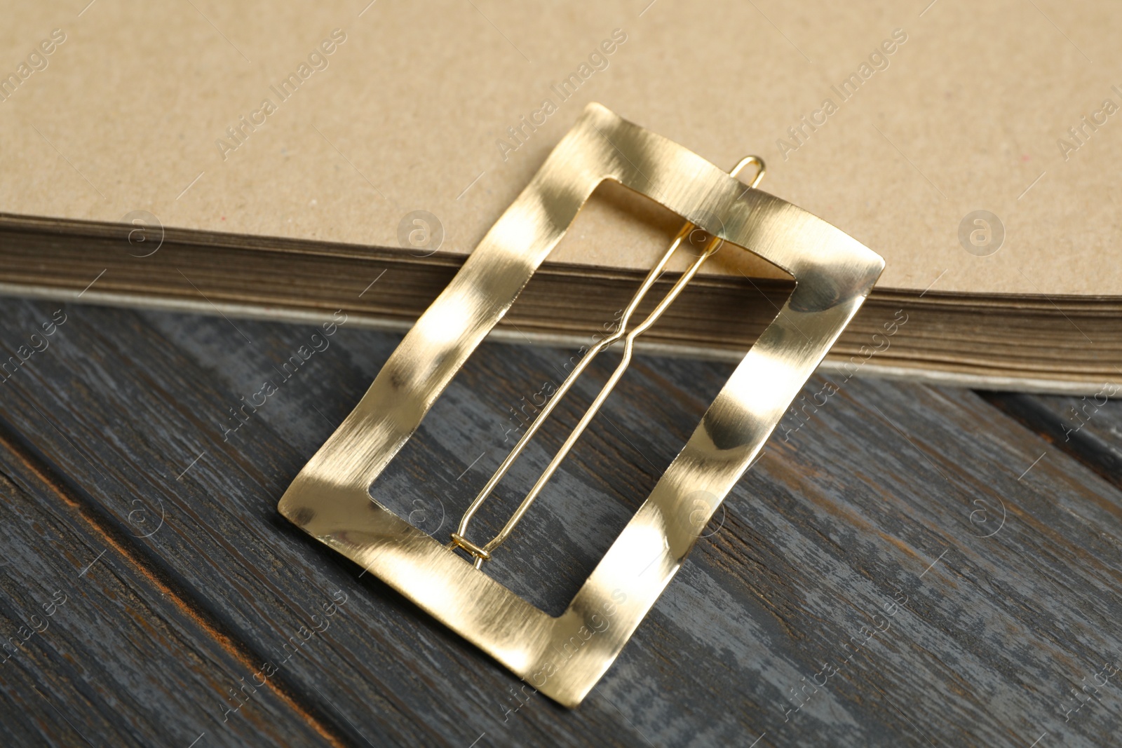 Photo of Stylish hair clip and book on black wooden table, above view