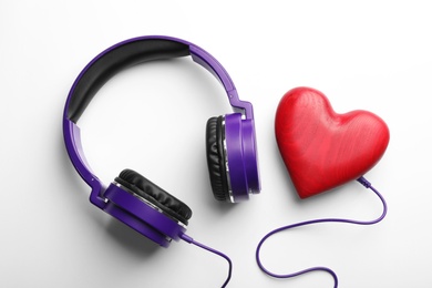 Decorative heart and modern headphones on white background, top view