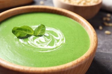 Photo of Bowl of healthy green soup with fresh spinach on grey table, closeup view