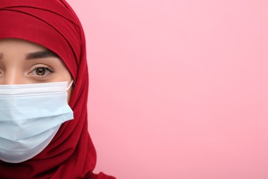 Photo of Muslim woman in hijab and medical mask on pink background, closeup. Space for text