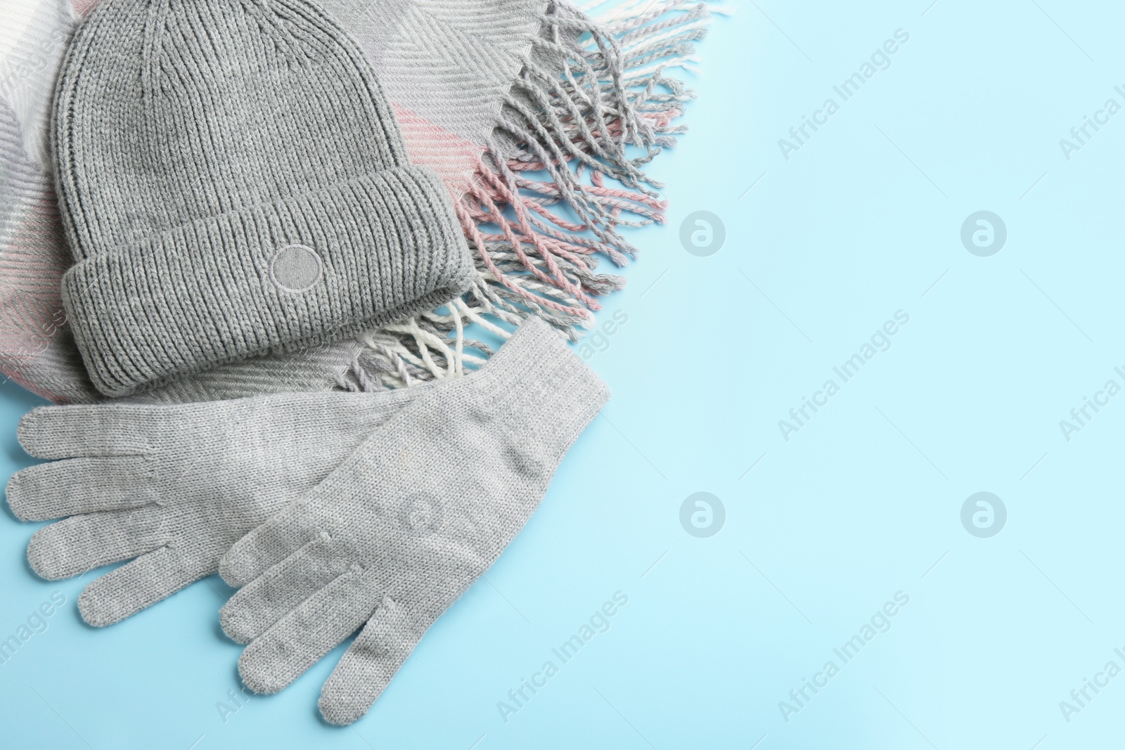 Photo of Stylish gloves, scarf and hat on light blue background, flat lay. Space for text