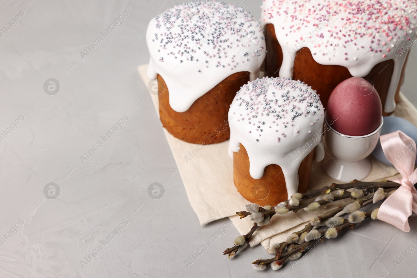 Photo of Tasty Easter cakes, decorated eggs and willow branches on grey table. Space for text