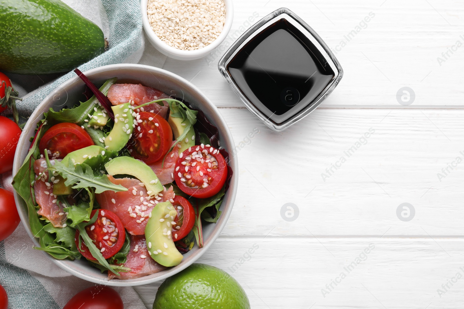 Photo of Tasty soy sauce, bowl with salad and ingredients on white wooden table, flat lay. Space for text