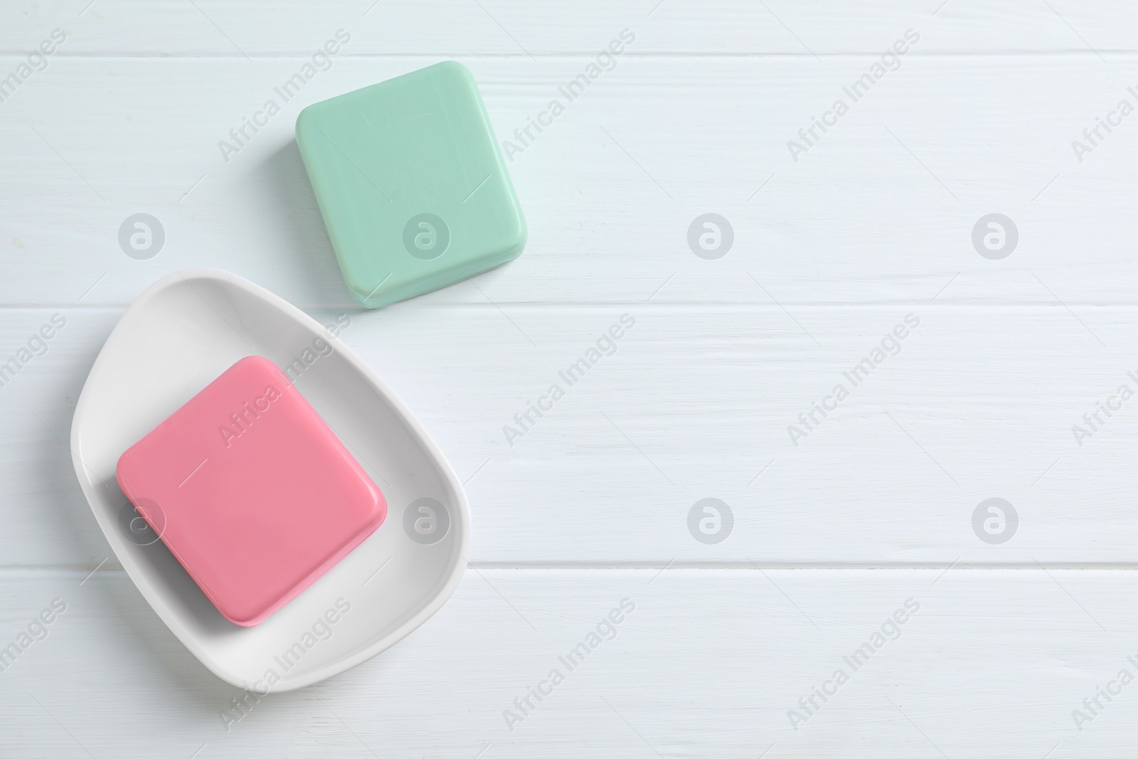 Photo of Soap bars on white wooden table, flat lay. Space for text