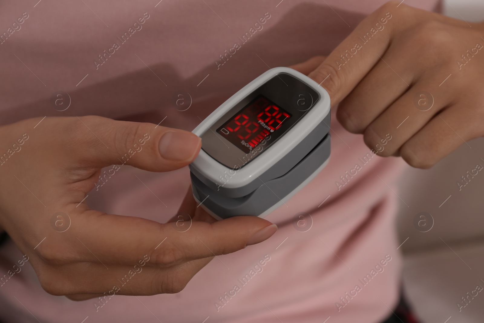 Photo of Woman measuring oxygen level with modern fingertip pulse oximeter, closeup