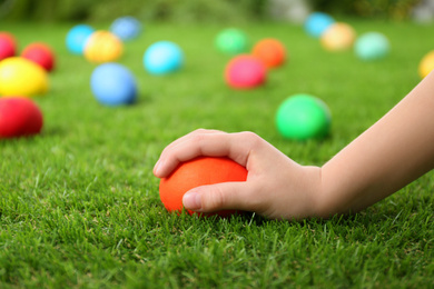 Photo of Little child taking Easter egg from green grass, closeup