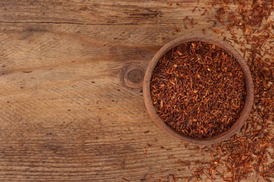 Photo of Dry rooibos leaves on wooden table, flat lay. Space for text