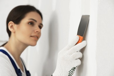 Photo of Worker plastering wall with putty knife, focus on hand