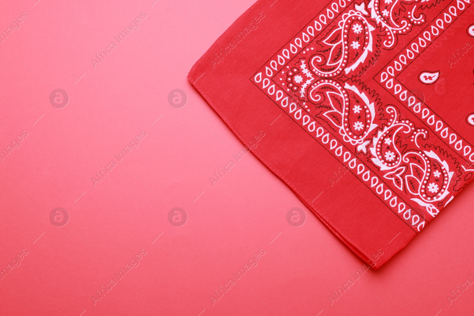 Photo of Folded bandana with paisley pattern on red background, top view. Space for text