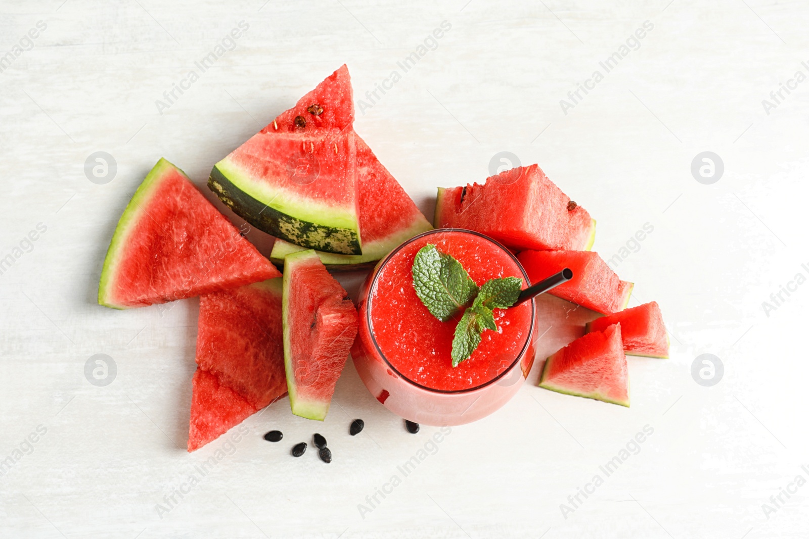 Photo of Summer watermelon drink in glass and sliced fresh fruit on table, top view