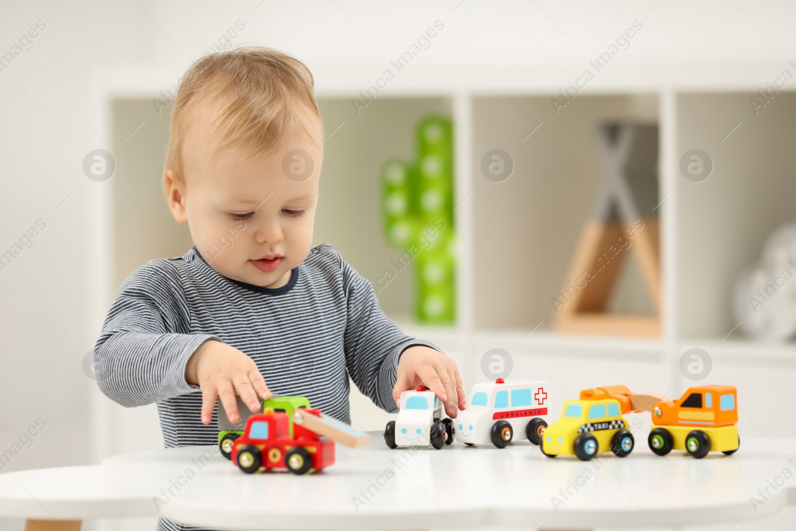 Photo of Children toys. Cute little boy playing with toy cars at white table in room, space for text