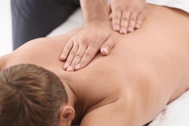 Photo of Relaxed man receiving back massage in wellness center