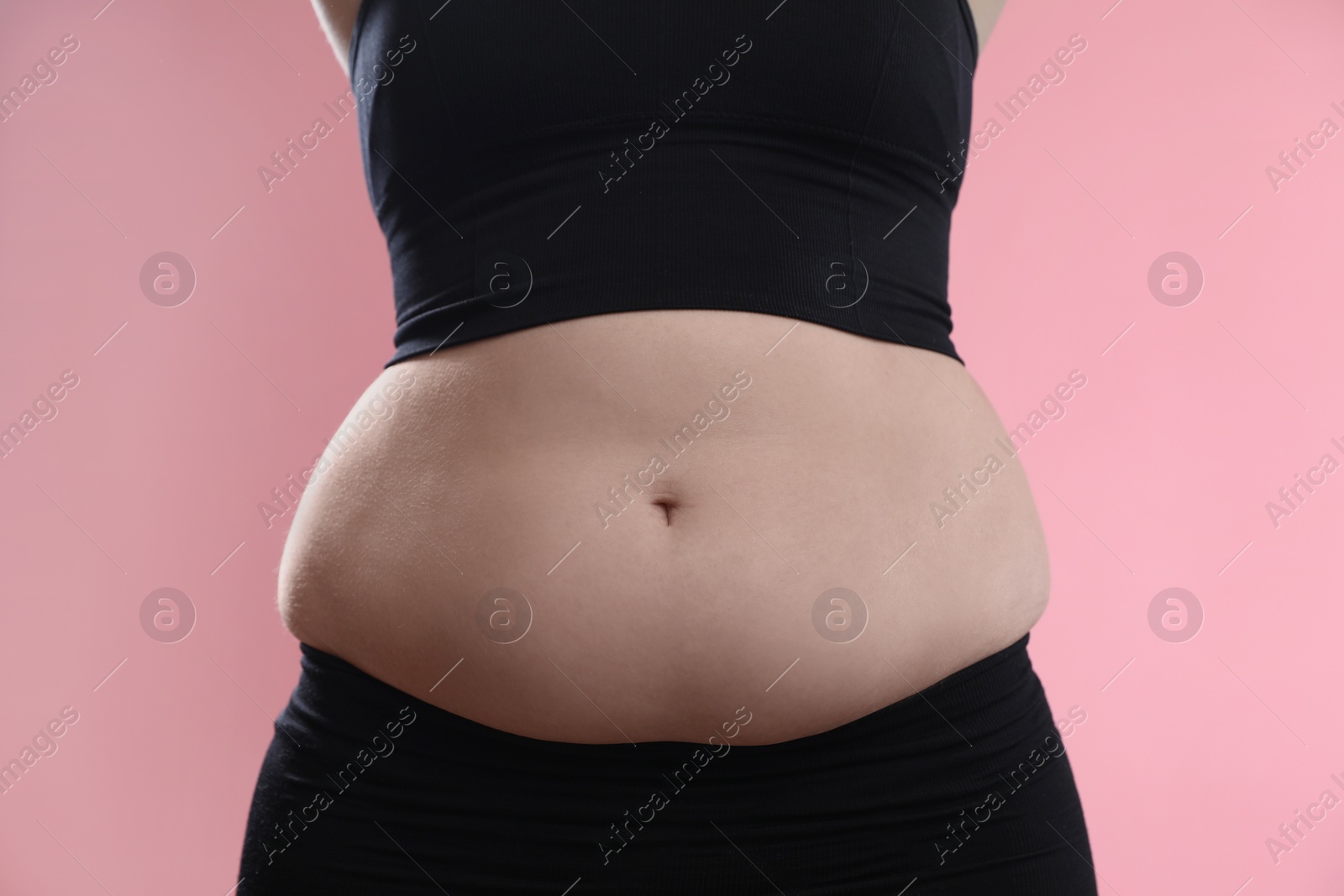 Photo of Woman with excessive belly fat on pink background, closeup. Overweight problem