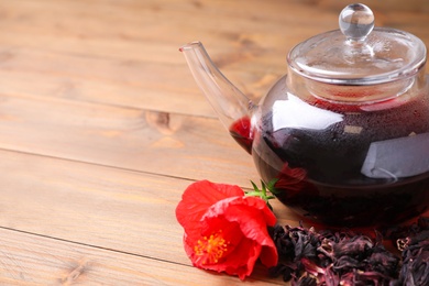Photo of Freshly brewed hibiscus tea on wooden table, closeup. Space for text