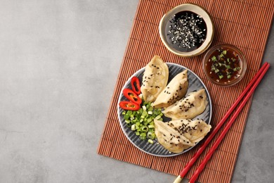 Photo of Delicious gyoza (asian dumplings) served on gray table, flat lay. Space for text