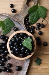 Ripe blackcurrants and leaves on wooden table, flat lay