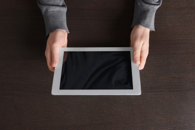 Man working with tablet at wooden table, top view