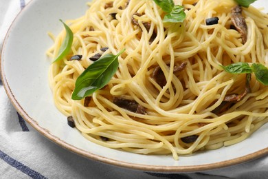 Photo of Delicious pasta with anchovies, olives and basil on plate, closeup