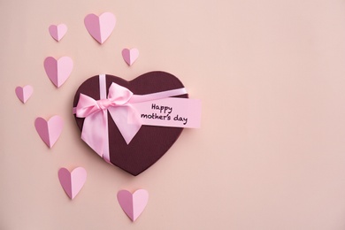 Photo of Gift box, paper hearts and greeting card with text "HAPPY MOTHER'S DAY" on color background