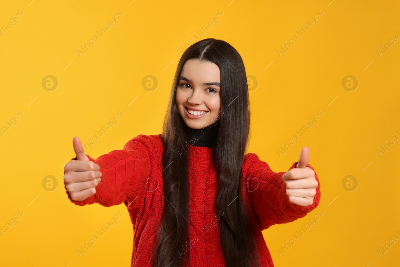 Photo of Teenage girl showing thumbs up on yellow background