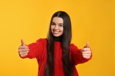 Photo of Teenage girl showing thumbs up on yellow background