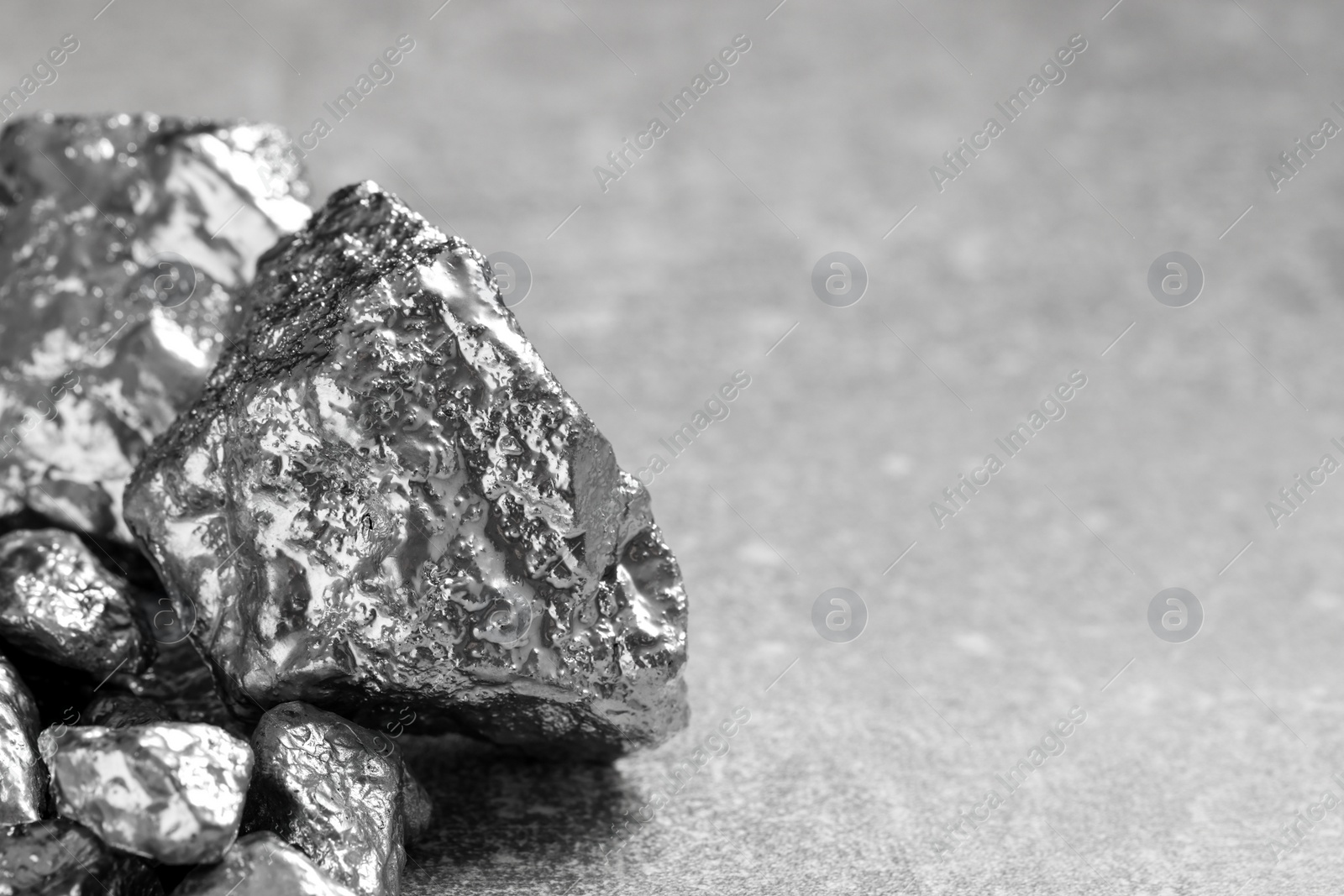 Photo of Pile of silver nuggets on light grey table, closeup. Space for text