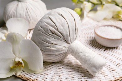 Photo of Herbal massage bags and flowers on grey table, closeup. Spa supply